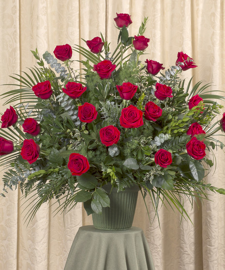 Sympathy arrangement of two dozen red roses and assorted foliage.