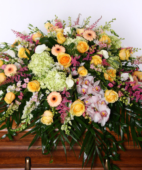 Casket spray of pink, white and peach flowers. 