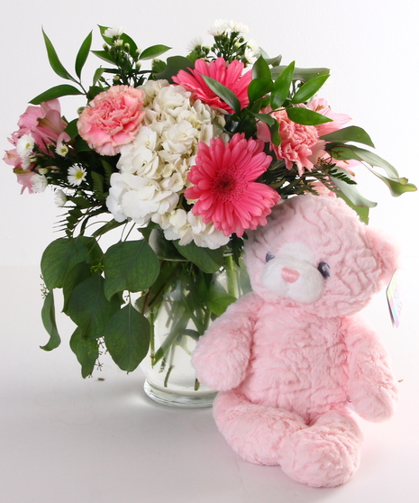 Mixed fresh flowers designed in a glass vase are delivered with a soft plush bear. 