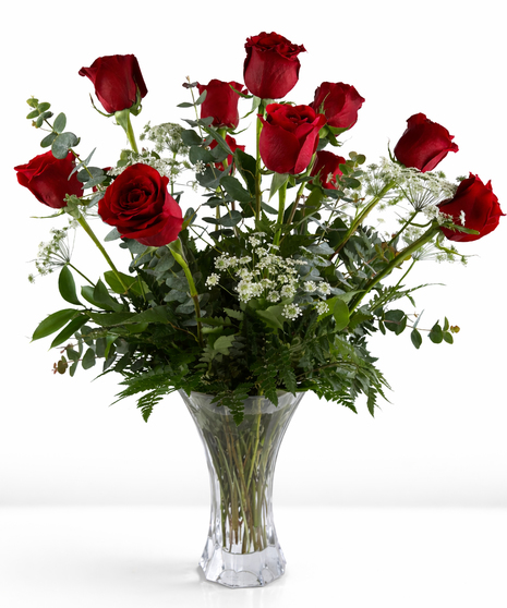 One dozen red roses and greenery in a clear glass vase.