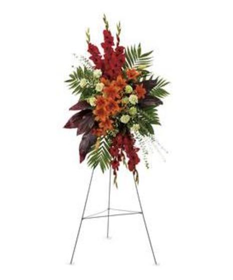 Sympathy spray of red and orange flowers with assorted greenery.
