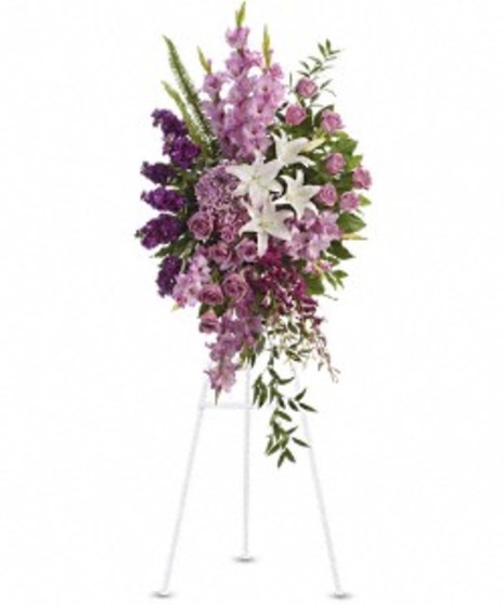 Sympathy spray of lavender, purple and white flowers presented on an easel. 