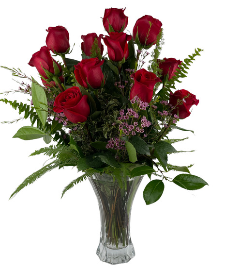 One dozen red roses and greenery in a clear glass vase.
