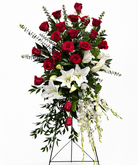 Sympathy spray of red roses and white lilies with greenery presented on an easel. 