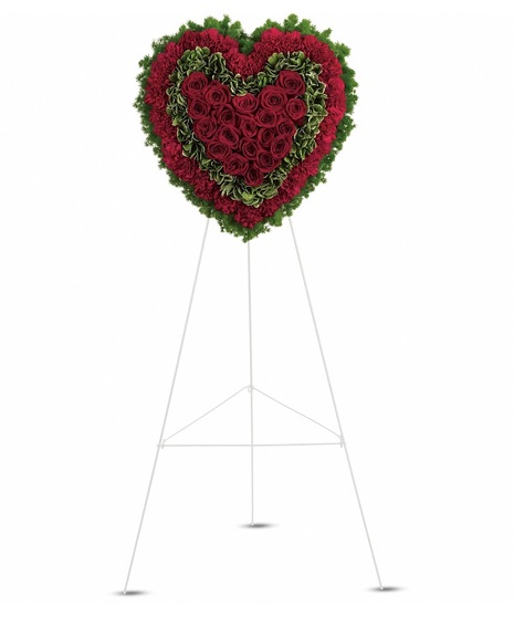 Sympathy heart of red roses and carnations with greenery presented on a wire easel. 