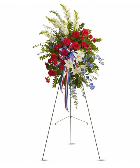 Patriotic sympathy spray of red, white and blue flowers presented on an easel. 